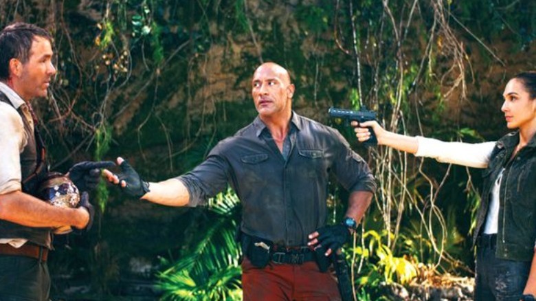 Dwayne Johnson, Ryan Reynolds and Gal Gadot pointing guns