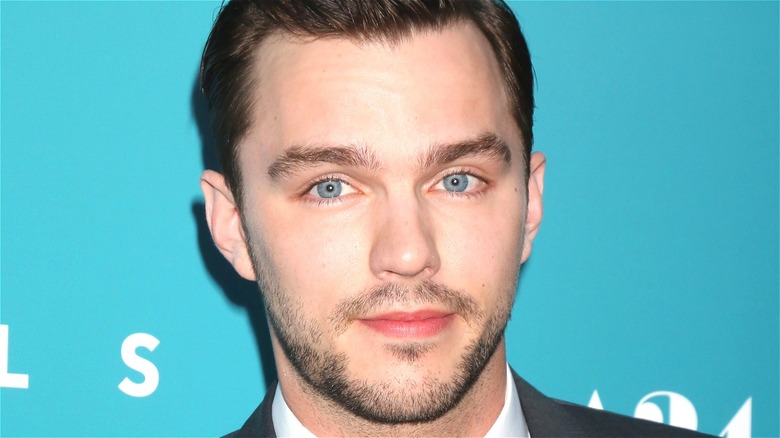 Nicholas Hoult smiling with teal background