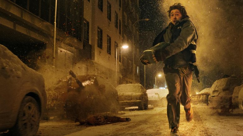 Bryan running down the street with monsters crashing around him in "Resident Evil" (2026)