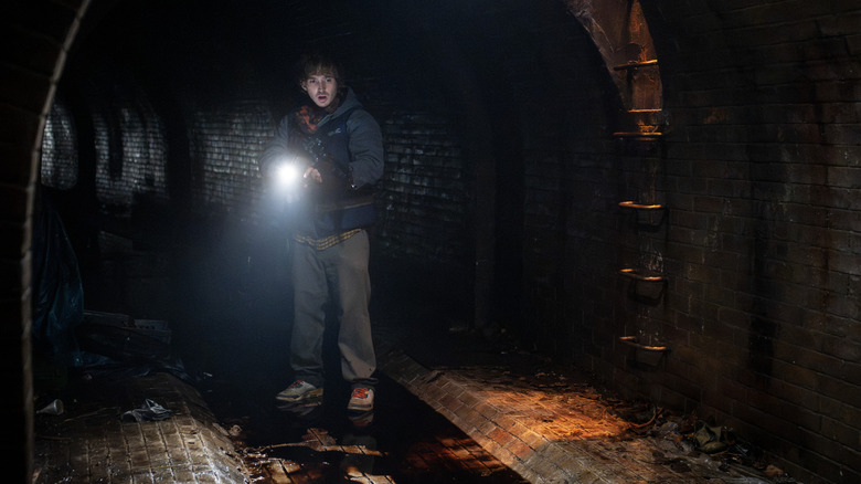 Bryan using a flashlight in the sewer in "Resident Evil" (2026)