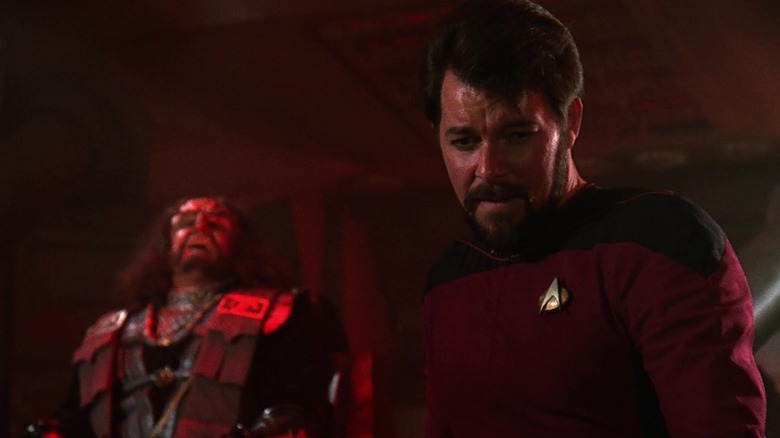 Riker looks down as a Klingon laughs in the background in Star Trek: The Next Generation (1987)