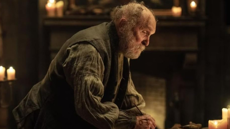 Jean-Pepe bending over to write something in The Pale Blue Eye (2022)