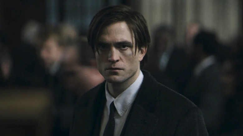 Bruce in a suit with his hair loose scowling in The Batman
