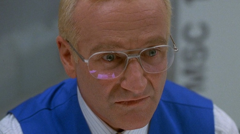 Robin Williams as Sy in One Hour Photo, wearing his bright blue vest and staring into space