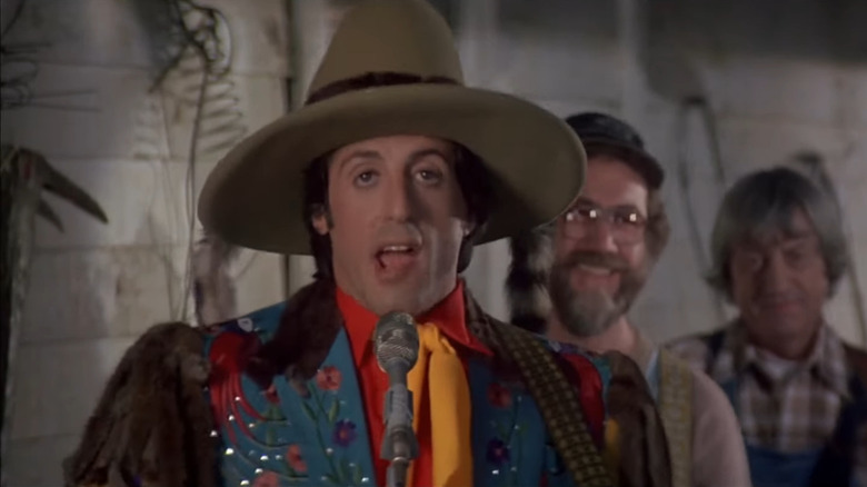Nick sings a country song in a silly costume in Rhinestone (1984)