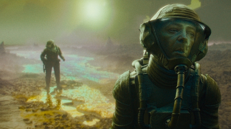 People in chemsuits walking on the surface of Nu-Earth in