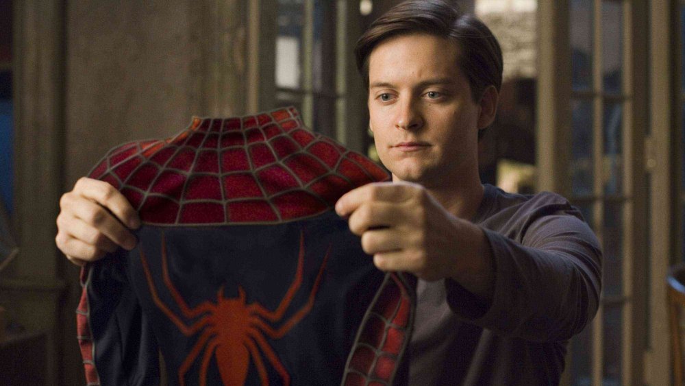 Tobey Maguire as Peter Parker inspecting his Spidey suit in Spider-Man