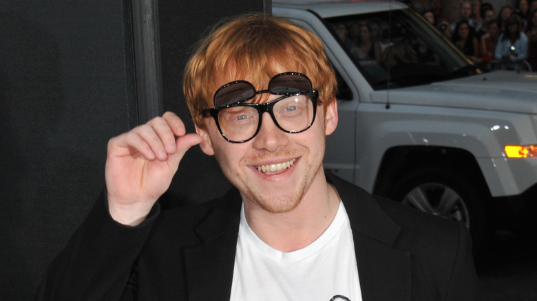 Grint wearing glasses and smiling at the camera