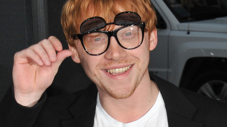 Grint wearing glasses and smiling at the camera