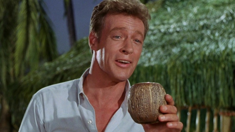 The Professor smiling while drinking from a coconut