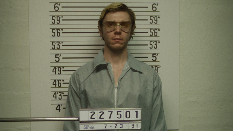 Evan Peters as Jeffrey Dalmer taking a mugshot