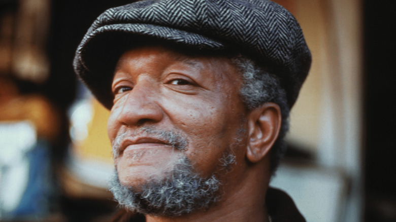 Redd Foxx smiling and wearing flat cap
