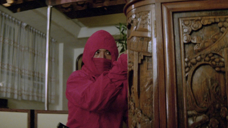 A pink-suited ninja hides behind a cabinet in "Ninja Terminator" (1985)