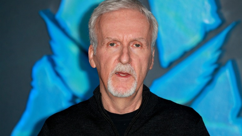 James Cameron standing in front of Avatar logo