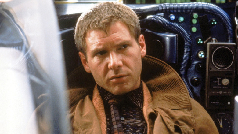 Deckard riding in a futuristic car in "Blade Runner" (1982)