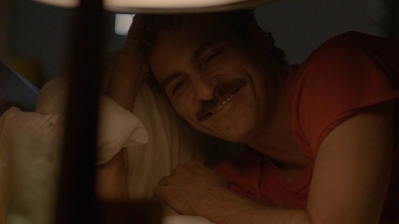 Theodore Twombly in Her, smiling in bed at night while looking at his nightstand