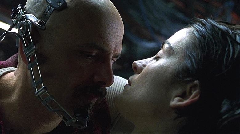 Cypher leaning in close to an unconscious Trinity in The Matrix