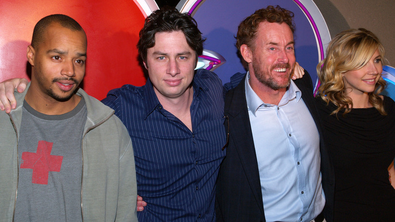 Actors Donald Faison, Zach Braff, John C. McGinley, and Sarah Chalke posing for photos in front of a colorful background