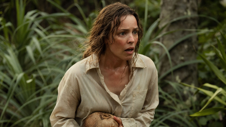 Linda walking through jungle nervously holding coconut