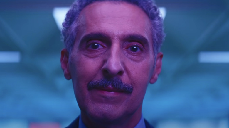 Irving smiling slightly bathed in pink and blue light