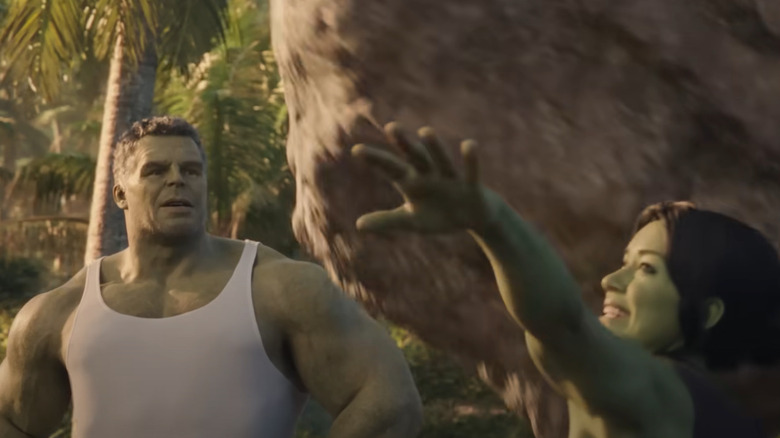 She-Hulk throwing a boulder while Hulk watches