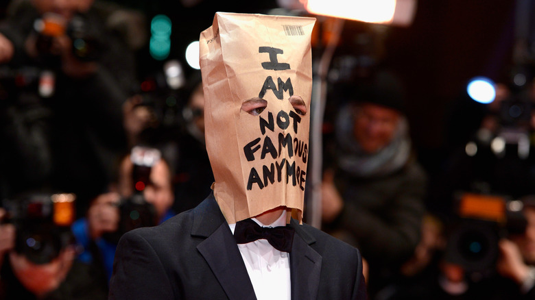 Shia LaBeouf wearing a bag on his head that says I Am Not Famous Anymore on a red carpet