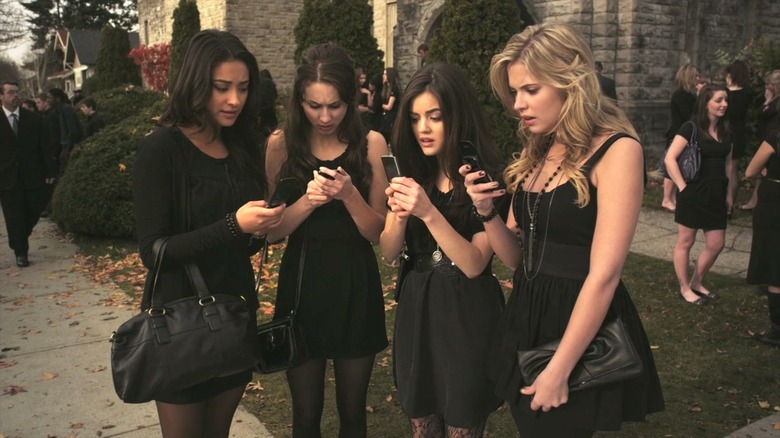 Aria, Spencer, Hanna, and Emily staring at their phones in Pretty Little Liars