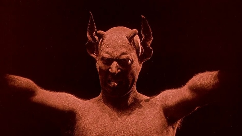 The Devil threatening someone in a dark room