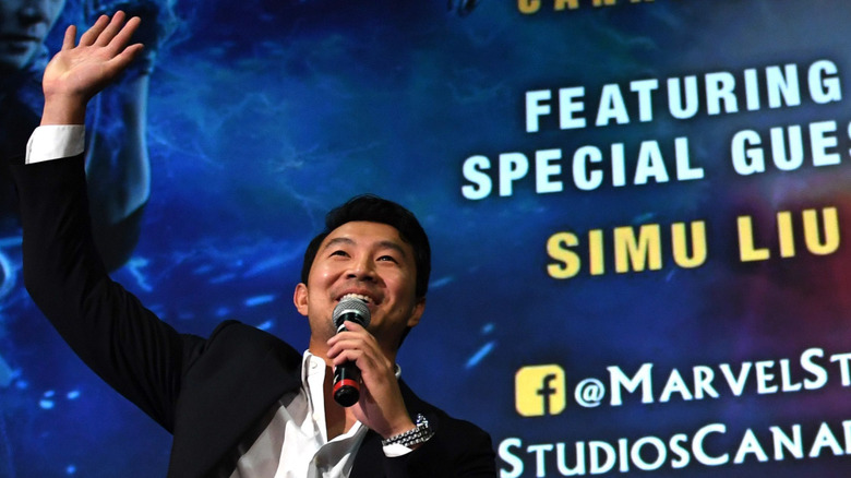 Simu Liu waves from onstage at the Toronto premiere of "Shang-Chi and The Legend of the Ten Rings"