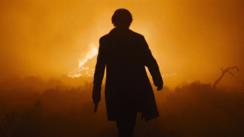 Silva silhouetted in front of a fire