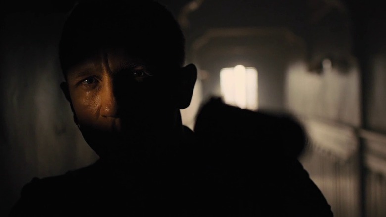 Bond aims a gun in the shadows