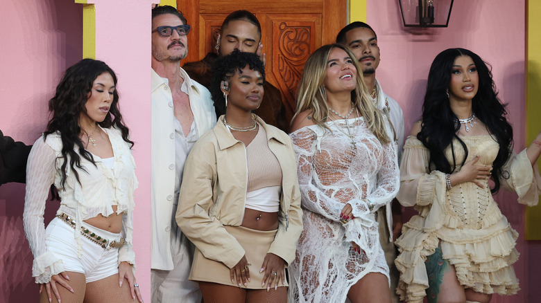 Cardi B, Karol G, and Pedro Pascal standing with dancers on the porch of the casita