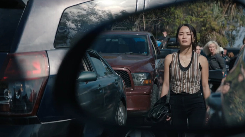 Cate Randa seen through a rearview mirror as she walks through gridlock traffic in Monarch: Legacy of Monsters Season 2 (2026)
