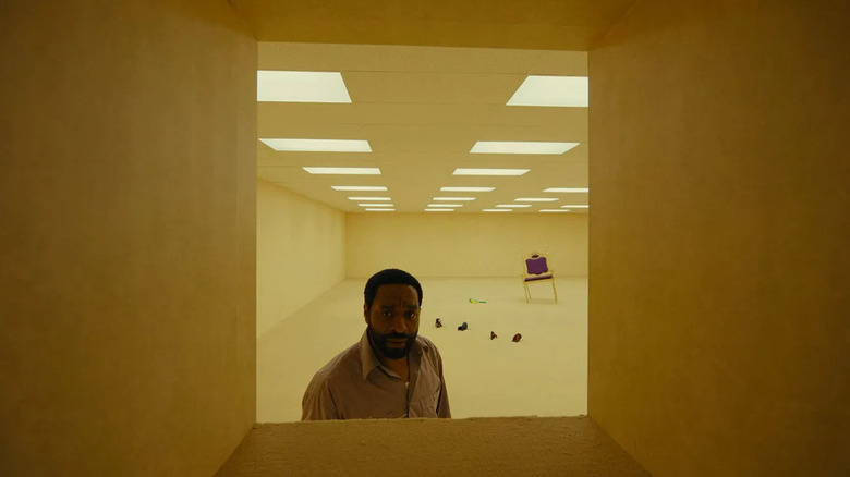 Clark retrieving a bag with toy parrots visible next to a throne in Backrooms (2026)
