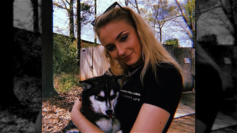 Sophie Turner holding her dog Waldo outside
