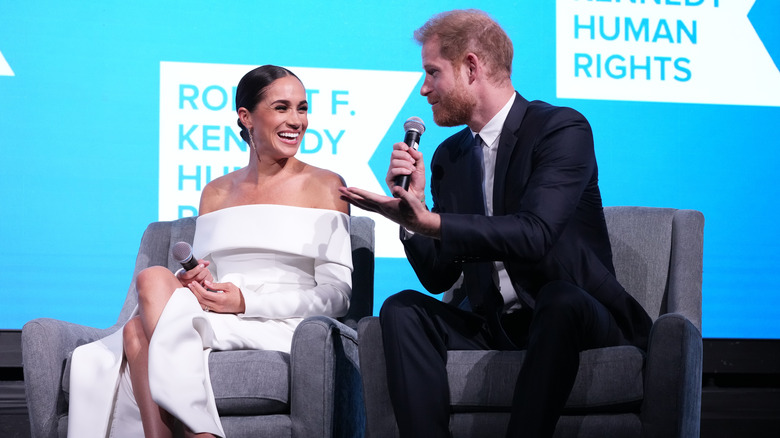 Harry and Meghan speaking and smiling together on stage