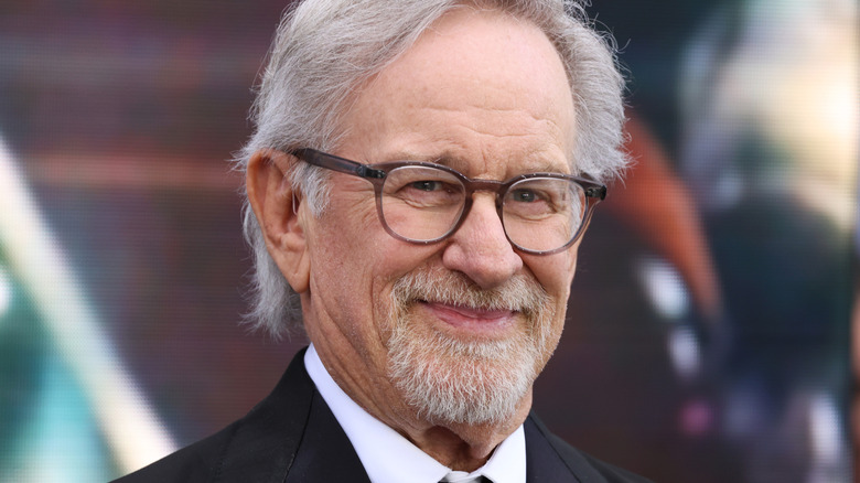Steven Spielberg smiling on a red carpet in a black suit