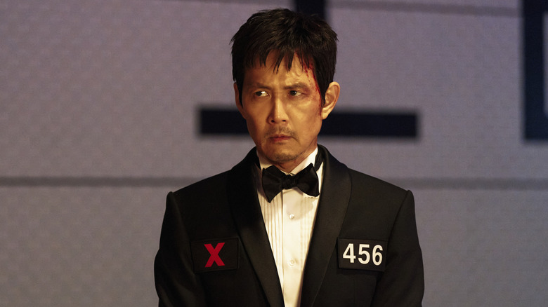 Gi-hun in a tuxedo with his number on it on Squid Game