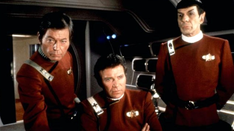 Kirk sitting flanked by Bones and Spock in 