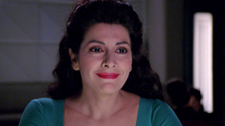 Troi sits smiling in Ten Forward in "Star Trek: The Next Generation" (1987-1994)