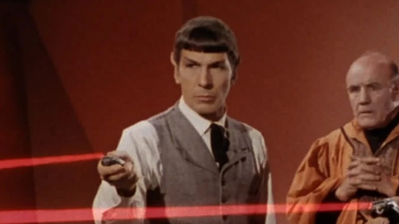 Spock wearing a waistcoat and tie, firing a phaser