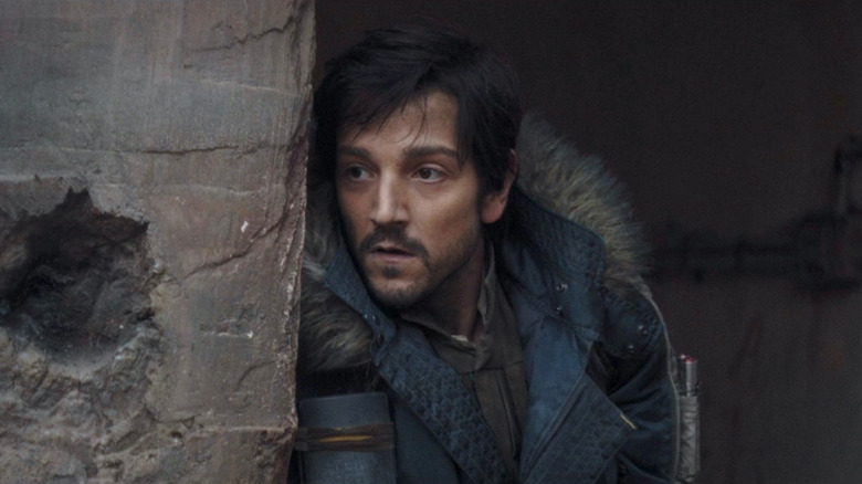 Cassian Andor leans against a stone wall