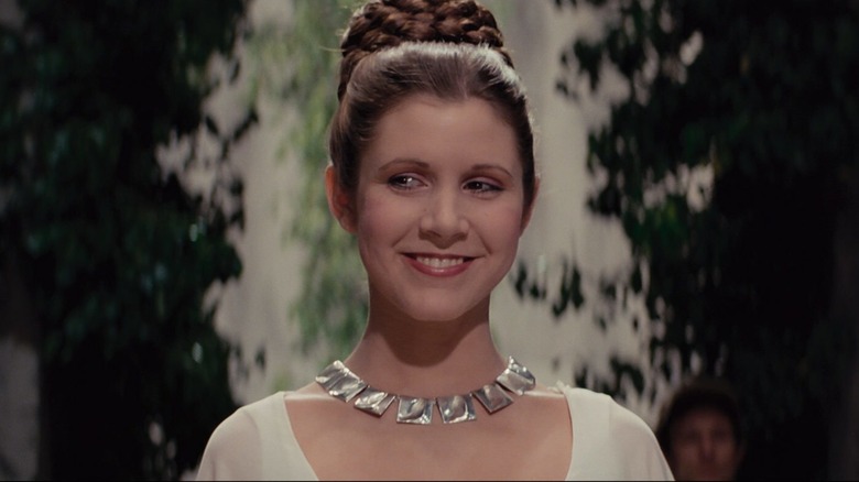 Princess Leia smiles in a white gown with her hair up in "Star Wars" (1977)