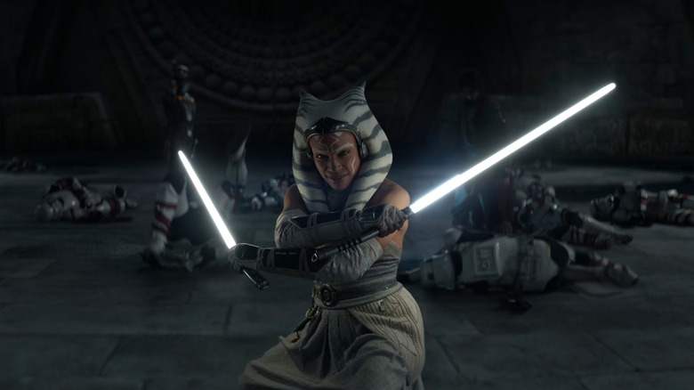 Ahsoka brandishing two white lightsabers, bodies of Stormtroopers behind her on the ground, in Ahsoka (2023)