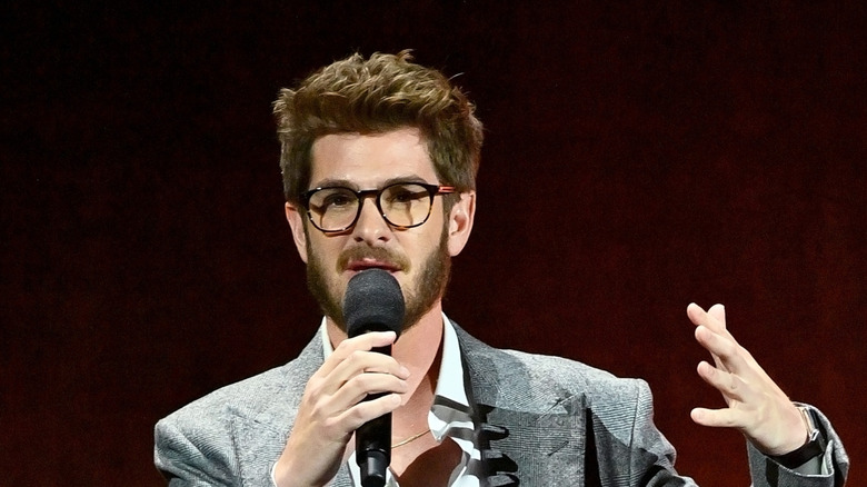 Andrew Garfield gestures and talks into a microphone
