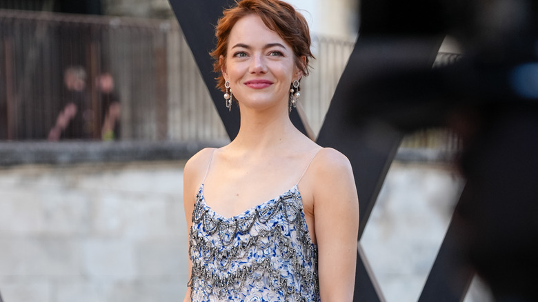 Emma Stone smiling in a blue dress outside