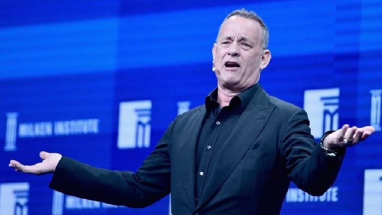 Tom Hanks raises his hands onstage