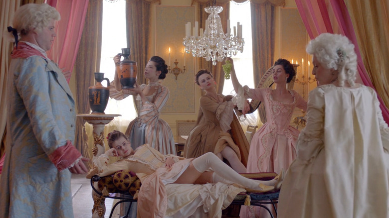 The women posing in gowns holding fruits and vases in Harlots (2017)
