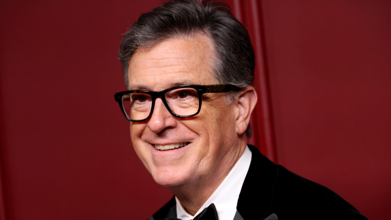 Stephen Colbert smiling and wearing glasses