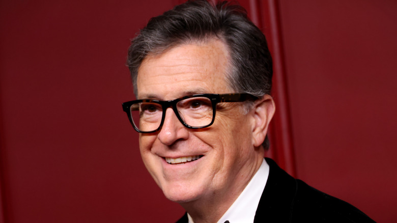 Stephen Colbert smiling and wearing glasses